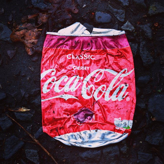 Three large black rubbish bags made of thick plastic and slightly crinkled, are placed on the pavement in front of a black metal fence with vertical bars. The bags appear to contain household waste an